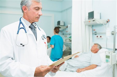 patient comfort - Doctor holding a chart in a bed ward Foto de stock - Sin royalties Premium, Código: 6109-06196266