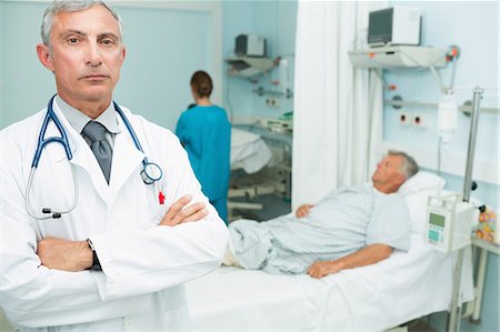 serious older woman looking at camera - Doctor with his arms crossed standing in a hospital ward Stock Photo - Premium Royalty-Free, Code: 6109-06196273