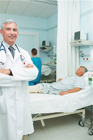 simsearch:6109-06196363,k - Smiling doctor with his arms crossed standing in a bed ward Stock Photo - Premium Royalty-Free, Code: 6109-06196272