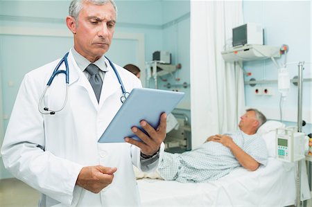 simsearch:6109-06196363,k - Males doctor holding a tactile tablet while standing Stock Photo - Premium Royalty-Free, Code: 6109-06196280