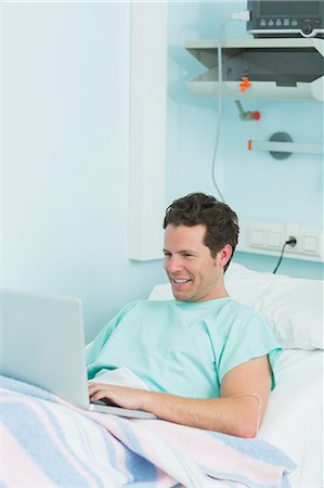 simsearch:6109-06196332,k - Joyful patient using a laptop while lying on a bed Foto de stock - Sin royalties Premium, Código: 6109-06196298