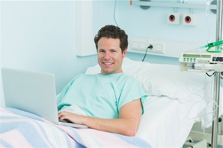simsearch:6109-06196332,k - Joyful patient with a laptop lying on a bed Foto de stock - Sin royalties Premium, Código: 6109-06196299