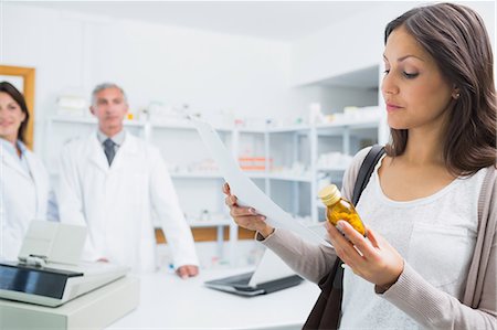 Female client holding a paper and pills while standing in a pharmacy Stock Photo - Premium Royalty-Free, Code: 6109-06196218