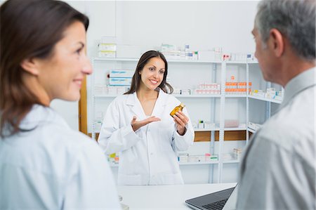 Female pharmacist holding a bottle of pills behind a counter Stock Photo - Premium Royalty-Free, Code: 6109-06196219