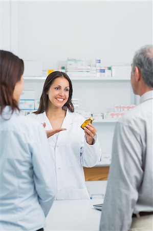 Pharmacist presenting a bottle of pills behind the counter of a pharmacy Stock Photo - Premium Royalty-Free, Code: 6109-06196222