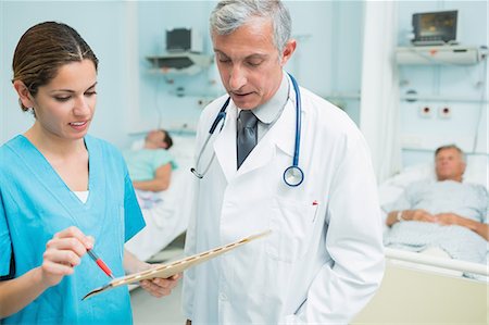 physician with older male - Male doctor and a nurse looking at files in a hospital ward Stock Photo - Premium Royalty-Free, Code: 6109-06196341