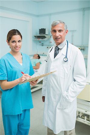 simsearch:6109-06196363,k - Nurse and doctor looking at files in a hospital with two patients Stock Photo - Premium Royalty-Free, Code: 6109-06196344