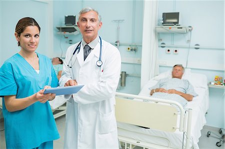 simsearch:6109-06196363,k - Male doctor and female nurse standing in a room while holding a tactile tablet Stock Photo - Premium Royalty-Free, Code: 6109-06196349