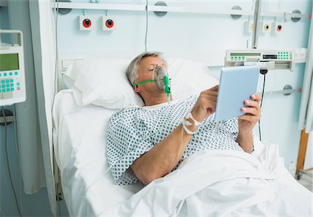 simsearch:6109-06196332,k - Patient lying on a bed with a mask while holding a tactile tablet Foto de stock - Sin royalties Premium, Código: 6109-06196373
