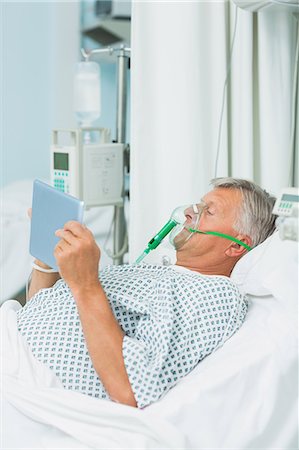 simsearch:6109-06196332,k - Senior male patient wearing an oxygen mask while using a tactile tablet Foto de stock - Sin royalties Premium, Código: 6109-06196379