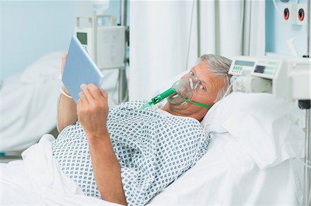 simsearch:6109-06196332,k - Senior patient holding a tactile tablet in his hands while wearing an oxygen mask Foto de stock - Sin royalties Premium, Código: 6109-06196381