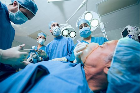 Surgery team in an operating theater operating an unconscious patient Stock Photo - Premium Royalty-Free, Code: 6109-06196384