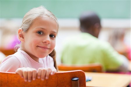 Smiling little girl sitting at school desk Stock Photo - Premium Royalty-Free, Code: 6109-06196388