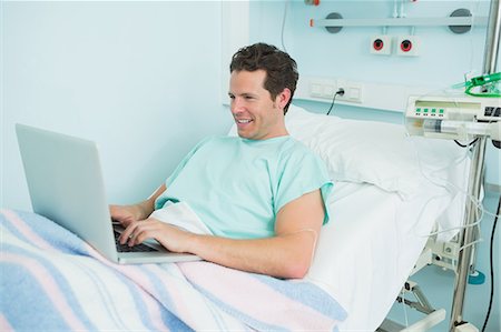 simsearch:6109-06196332,k - Joyful patient typing on a laptop while lying on a bed Foto de stock - Sin royalties Premium, Código: 6109-06196300