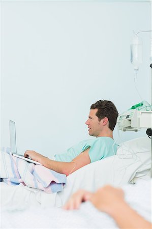 simsearch:6109-06196332,k - Focus shot of a male patient using a laptop while lying on a bed Foto de stock - Sin royalties Premium, Código: 6109-06196307