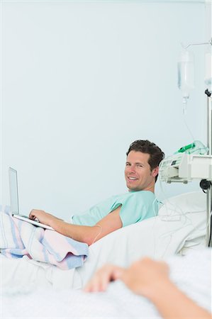 simsearch:6109-06196332,k - Focus shot of a male patient typing on a laptop while lying on a bed Foto de stock - Sin royalties Premium, Código: 6109-06196308