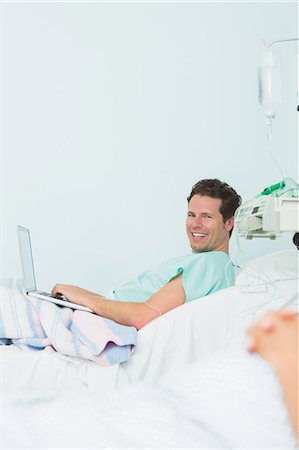 simsearch:6109-06196332,k - Focus shot of a happy male patient typing on a laptop while lying on a bed Foto de stock - Sin royalties Premium, Código: 6109-06196310