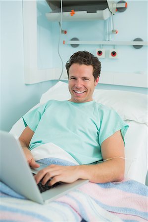 simsearch:6109-06196332,k - Patient using a laptop while lying on a bed and laughing Foto de stock - Sin royalties Premium, Código: 6109-06196316