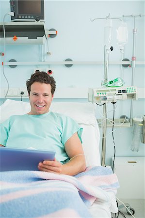 simsearch:6109-06196332,k - Happy male patient using a tactile tablet while lying on a bed Foto de stock - Sin royalties Premium, Código: 6109-06196322