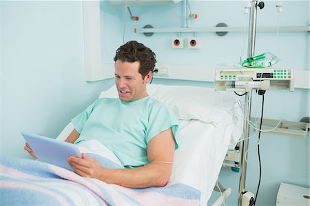 simsearch:6109-06196332,k - Happy patient holding a tactile tablet while lying on a bed Foto de stock - Sin royalties Premium, Código: 6109-06196325