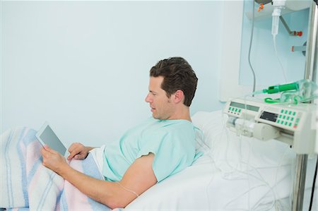 simsearch:6109-06196332,k - Male patient touching a tactile tablet while lying on a bed Foto de stock - Sin royalties Premium, Código: 6109-06196333