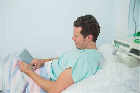 simsearch:6109-06196332,k - Male patient touching a tactile tablet while lying on a bed Foto de stock - Sin royalties Premium, Código: 6109-06196330