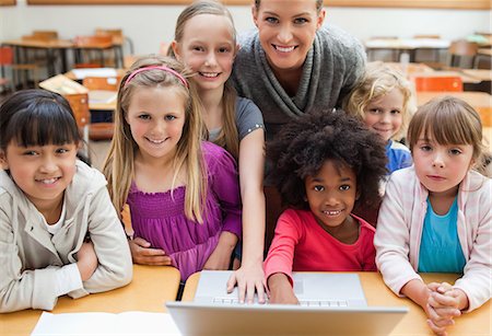 photo teacher with students in class - Smiling teacher with students and laptop Stock Photo - Premium Royalty-Free, Code: 6109-06196550