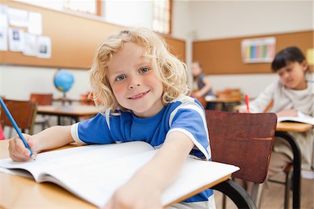 Smiling boy sitting at desk with exercise book Stock Photo - Premium Royalty-Free, Code: 6109-06196536