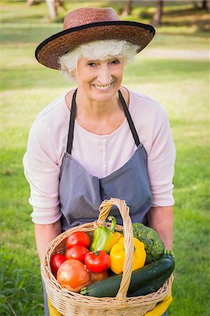 Smiling elderly woman carrying basket of vegetables Photographie de stock - Premium Libres de Droits, Code: 6109-06684865