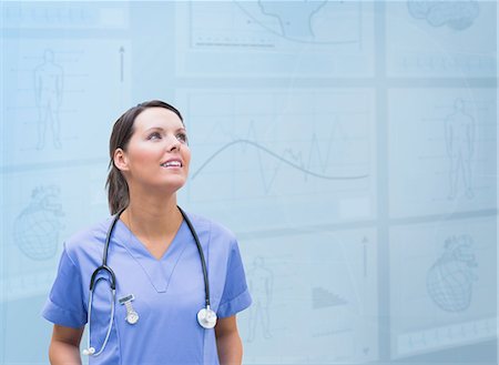 Nurse looking up against blue digital background Stock Photo - Premium Royalty-Free, Code: 6109-06685033