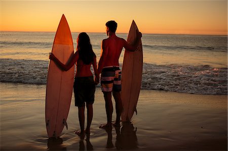 romantic beach sunset - Couple hand in hand holding surfboards on the beach Stock Photo - Premium Royalty-Free, Code: 6109-06781707