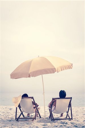 People relaxing on the beach reclining on deck chairs Stock Photo - Premium Royalty-Free, Code: 6109-06781992