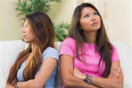 siblings conflict - Two annoyed sisters sitting on a couch in the living room Stock Photo - Premium Royalty-Free, Code: 6109-07497143