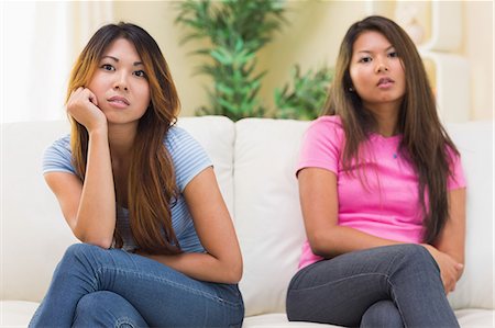 different people - Annoyed sisters sitting together on a couch in the living room Stock Photo - Premium Royalty-Free, Code: 6109-07497147