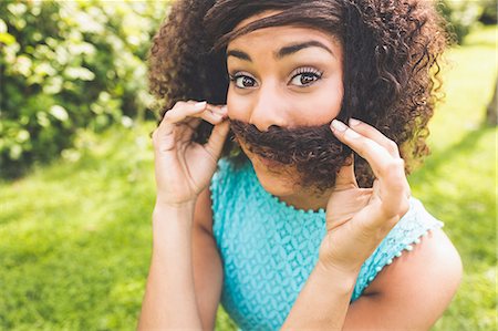 funny fashions - Gorgeous content brunette pretending having mustache in nature Stock Photo - Premium Royalty-Free, Code: 6109-07497272