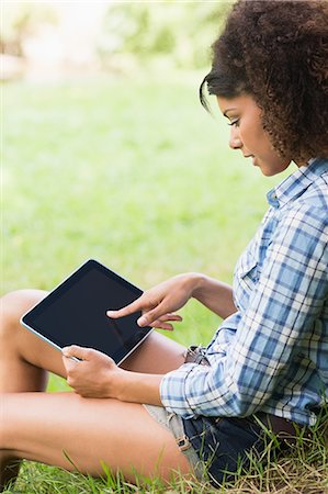 Gorgeous serious brunette leaning against tree using tablet in nature Stock Photo - Premium Royalty-Free, Code: 6109-07497281