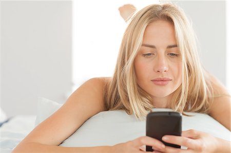 simsearch:6109-07497311,k - Happy blonde lying on her pillow sending a text at home in bedroom Stock Photo - Premium Royalty-Free, Code: 6109-07497393