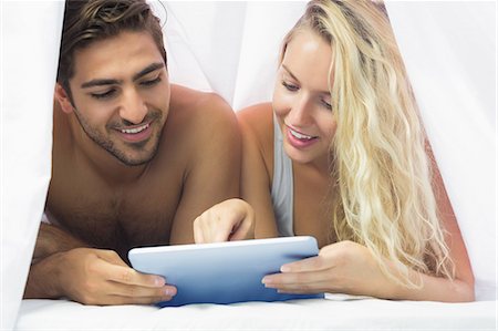 simsearch:6109-07497311,k - Cheerful couple lying under the sheet using a tablet at home in bedroom Stock Photo - Premium Royalty-Free, Code: 6109-07497326