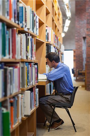 Serious librarian working at a desk in library in a college Stock Photo - Premium Royalty-Free, Code: 6109-07497461