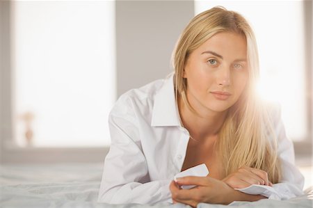 simsearch:6109-07497311,k - Beautiful blonde wearing white mens shirt lying on bed  at home in bedroom Stock Photo - Premium Royalty-Free, Code: 6109-07497410
