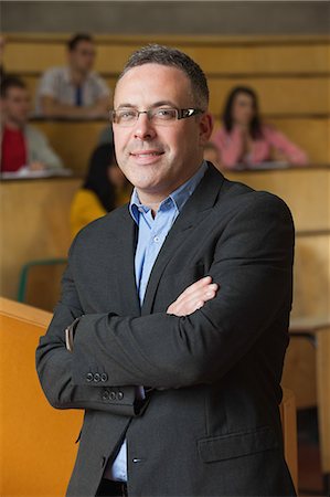 photo teacher with students in class - Lecturer smiling at camera in front of his class in lecture hall in college Stock Photo - Premium Royalty-Free, Code: 6109-07497666