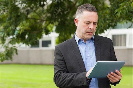 person concentrating computer - Serious lecturer using his tablet outside on campus at the university Stock Photo - Premium Royalty-Free, Code: 6109-07497692