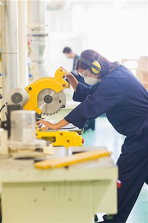 electric saw - Focused trainee sawing piece of wood in workshop Stock Photo - Premium Royalty-Free, Code: 6109-07497979