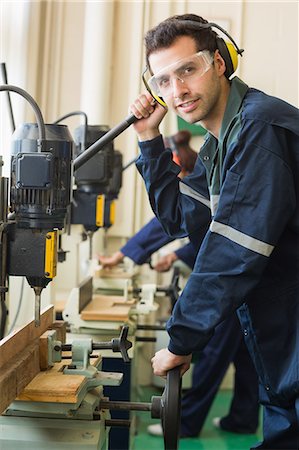 simsearch:400-07899762,k - Smiling craftsman with safety glasses drilling a piece of wood in workshop Stock Photo - Premium Royalty-Free, Code: 6109-07497985