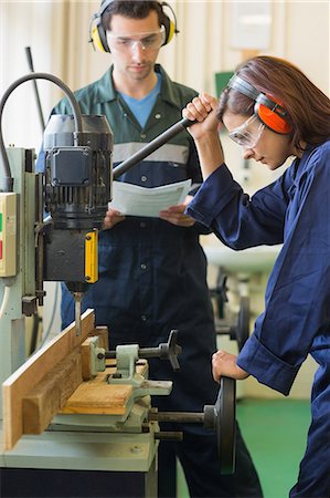 Focused trainee using drill in workshop Photographie de stock - Premium Libres de Droits, Code: 6109-07497990