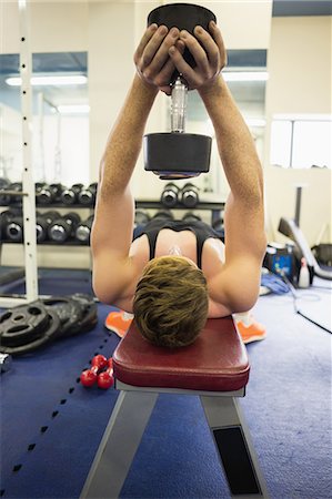 simsearch:6109-07497839,k - Man holding dumbbell over head in weights room of gym Stock Photo - Premium Royalty-Free, Code: 6109-07497903