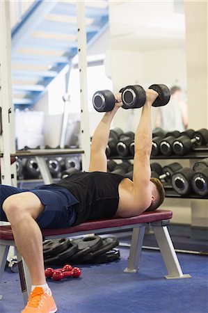 simsearch:6109-07497839,k - Muscular attractive man lying on bench holding dumbbells in weights room of gym Stock Photo - Premium Royalty-Free, Code: 6109-07497908