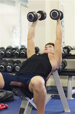 simsearch:6109-07497839,k - Muscular man lying on bench training with dumbbells in weights room of gym Stock Photo - Premium Royalty-Free, Code: 6109-07497910