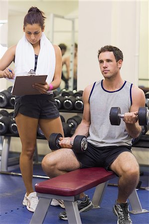 simsearch:6109-07497839,k - Trainer taking notes of muscular man lifting dumbbells in weights room of gym Stock Photo - Premium Royalty-Free, Code: 6109-07497939