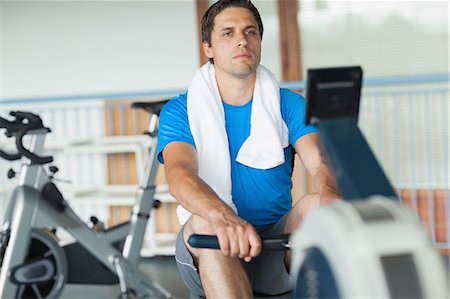 simsearch:400-05677902,k - Determined young man working out on row machine in fitness studio Photographie de stock - Premium Libres de Droits, Code: 6109-07498055